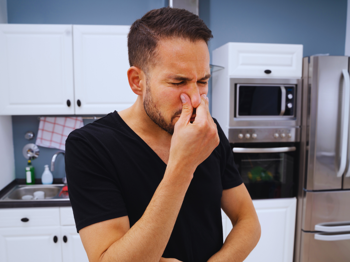 Man plugging nose from bad garbage disposal smell